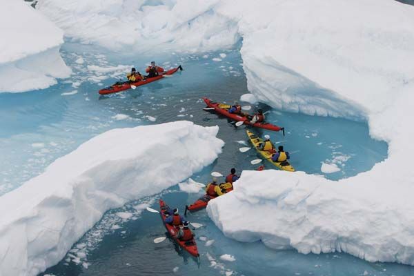Kayakers paddling alongside Antarctic icebergs during expedition